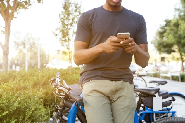 Man leaning on bike looking at phone.