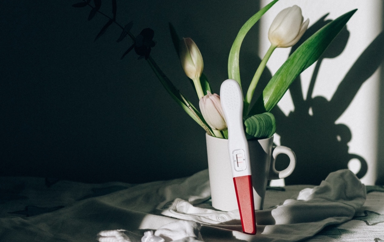 Positive ovulation test leaning on vase of flowers.