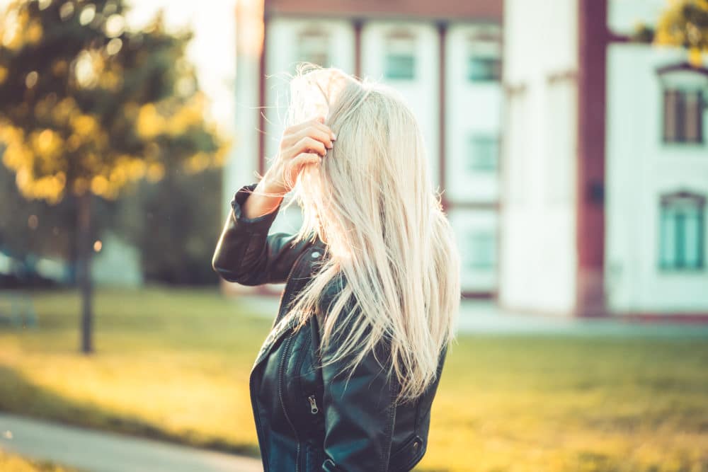 Woman with back to the camera running fingers through her hair.