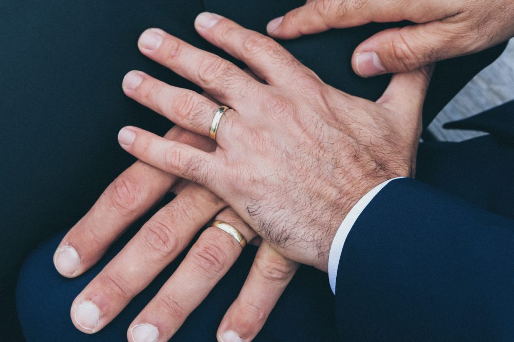 Two hands with gold wedding bands lying on top of eachother.