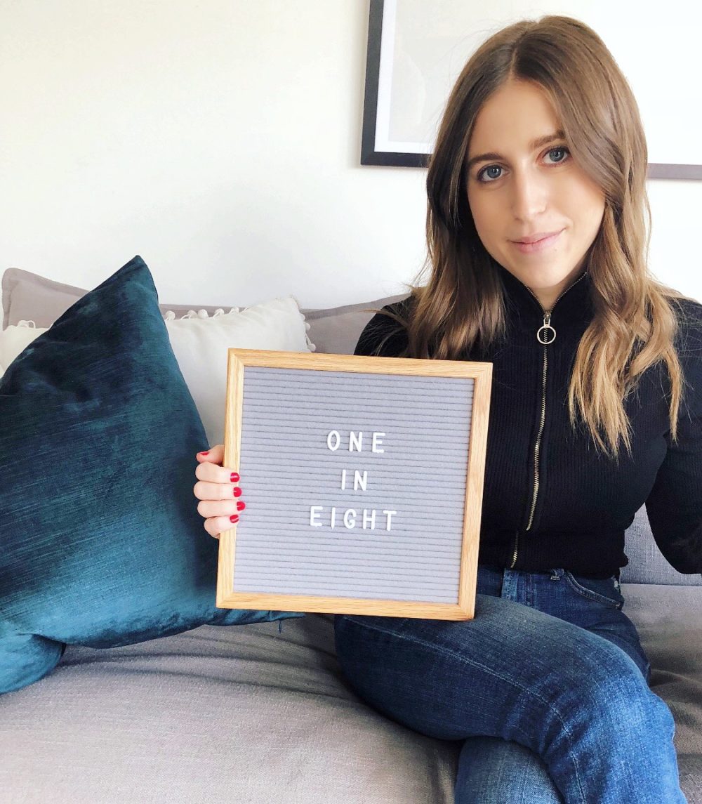 Arielle holding sign that reads 1 in 8