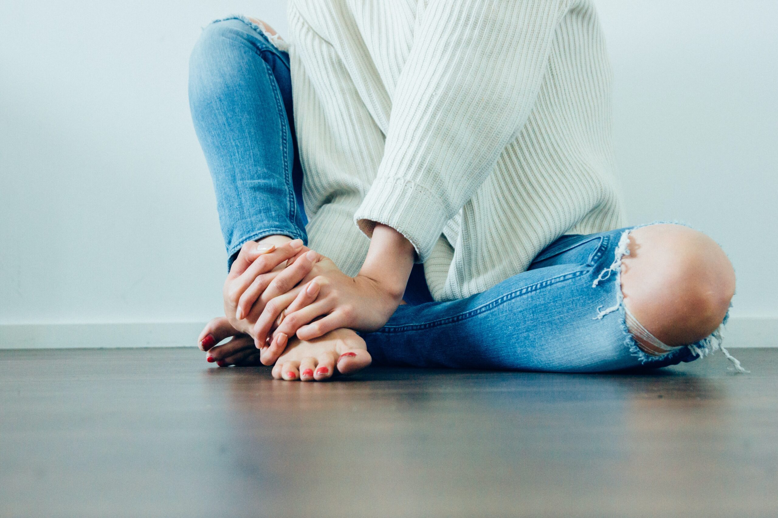 Woman in ripped jeans sitting on the floor.