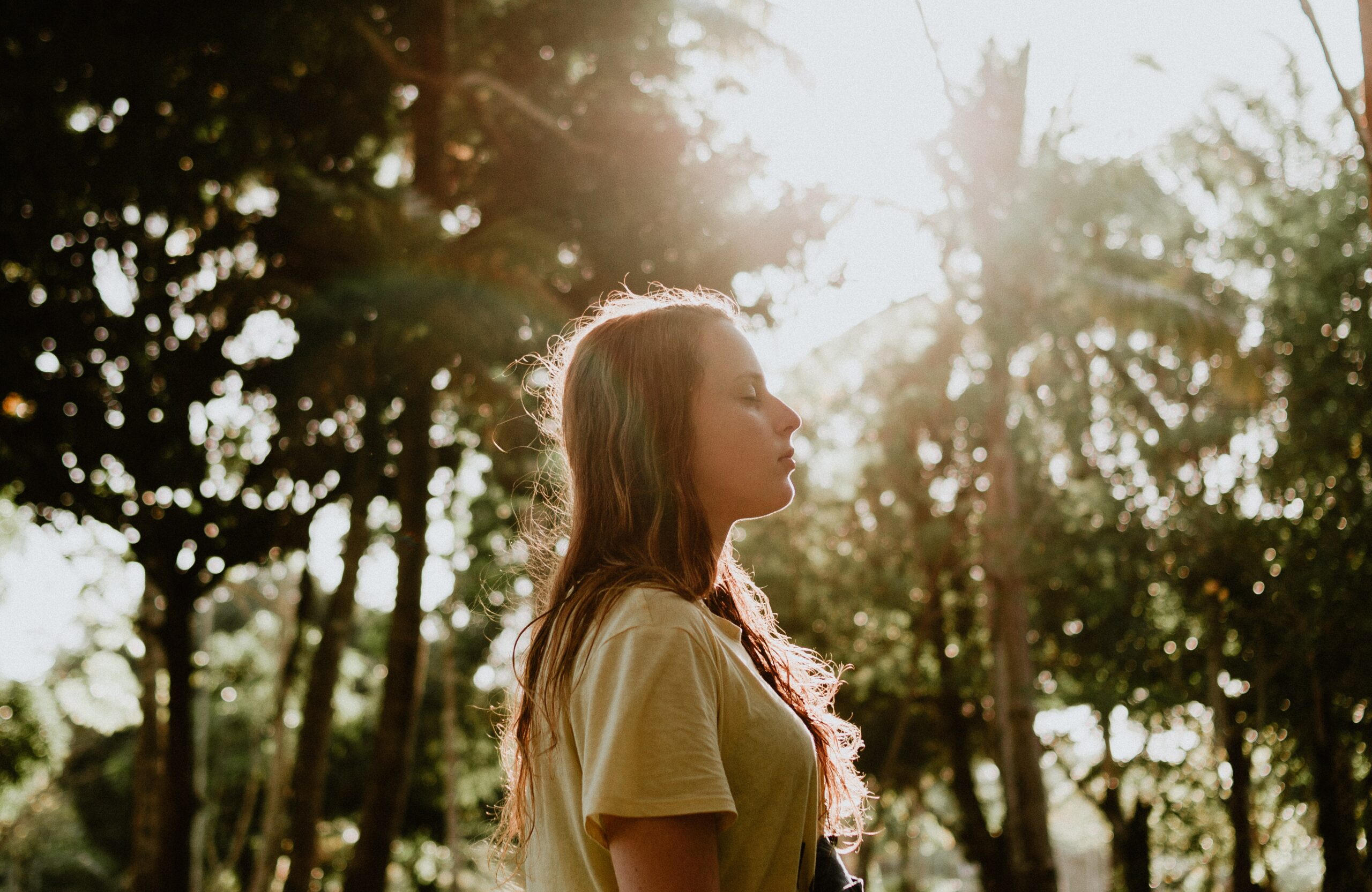 Woman walking and sun shining through trees.