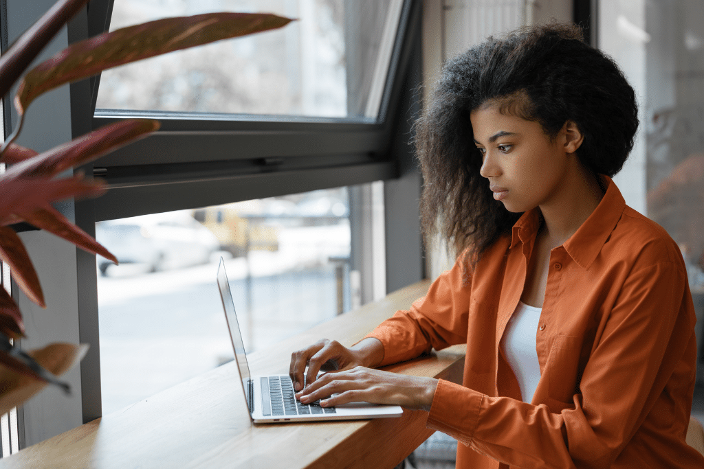 A women sits at a table and searches on her laptop.