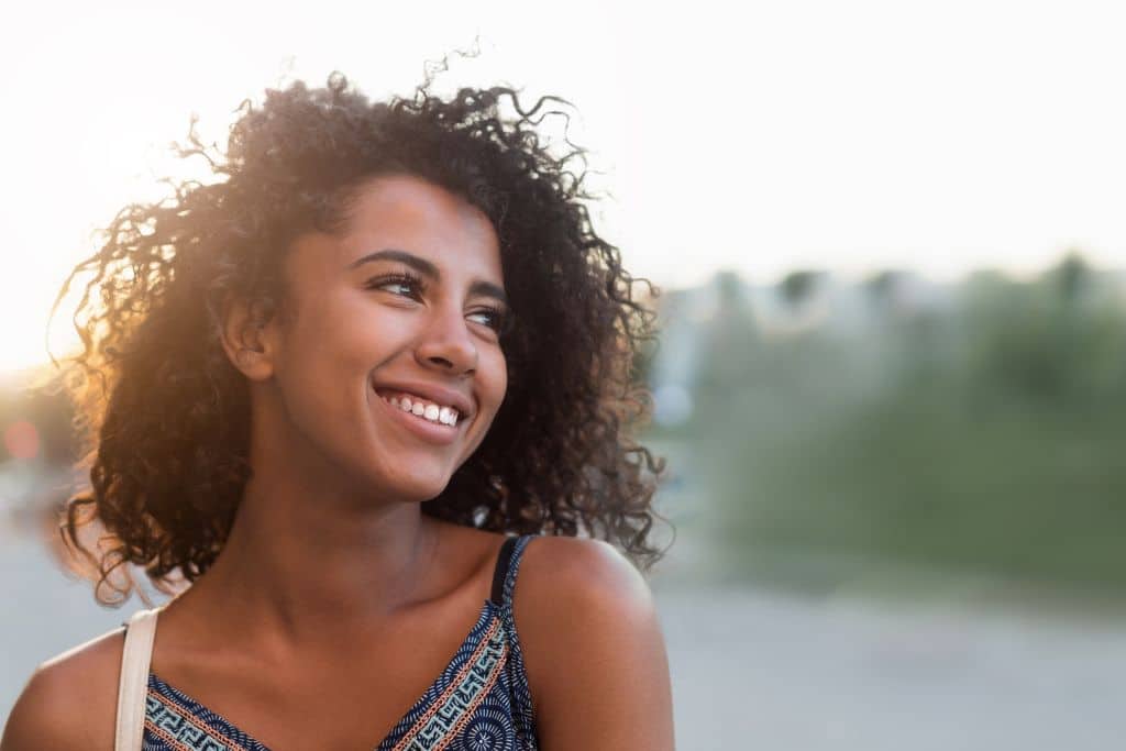 A woman smiles into the distance.