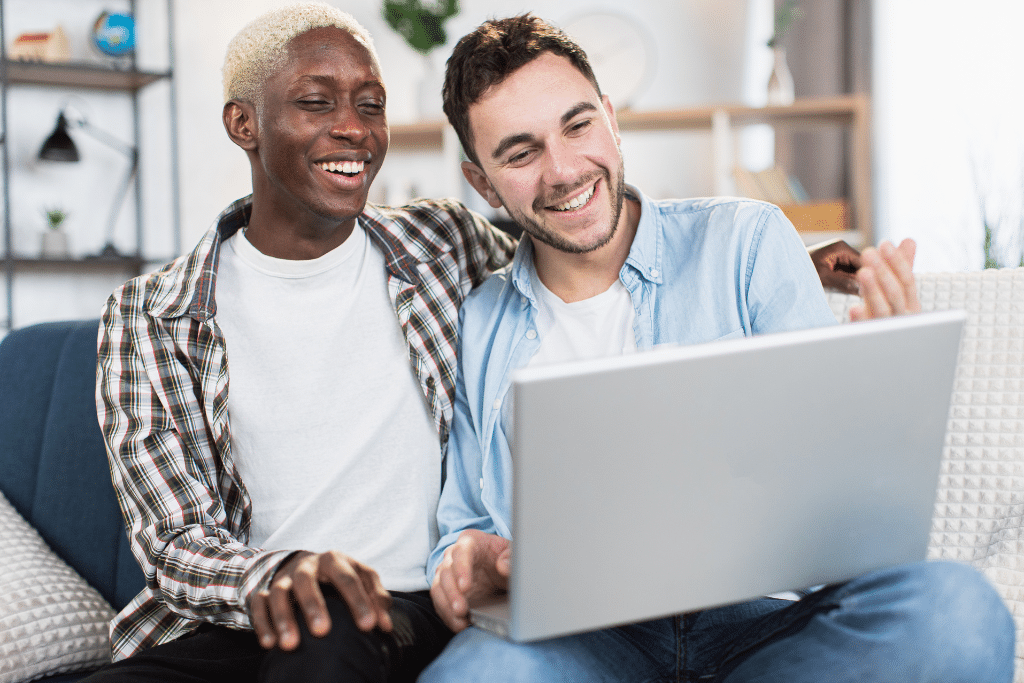 A couple sits on the couch and looks at a computer.
