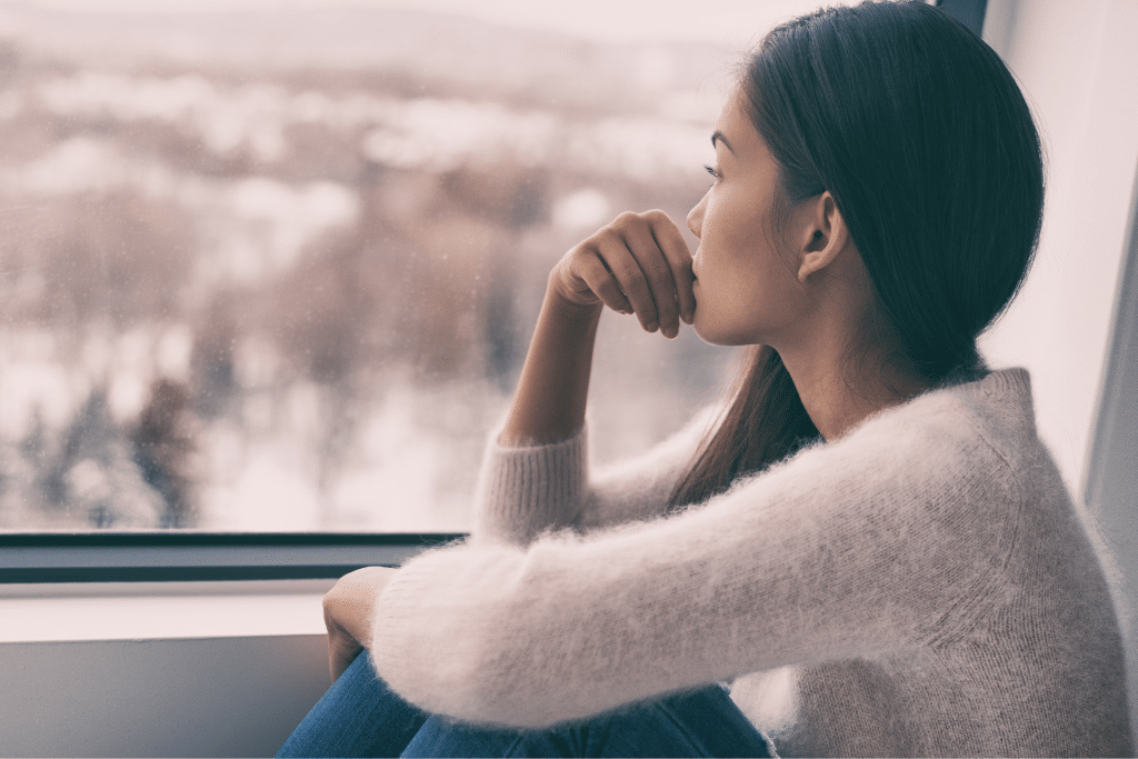 A woman looks out the window sadly.