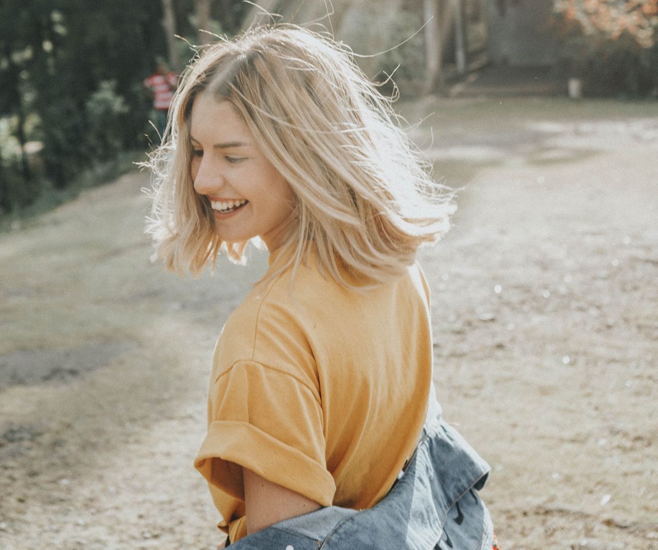 A woman smiles while the sun sets behind her.
