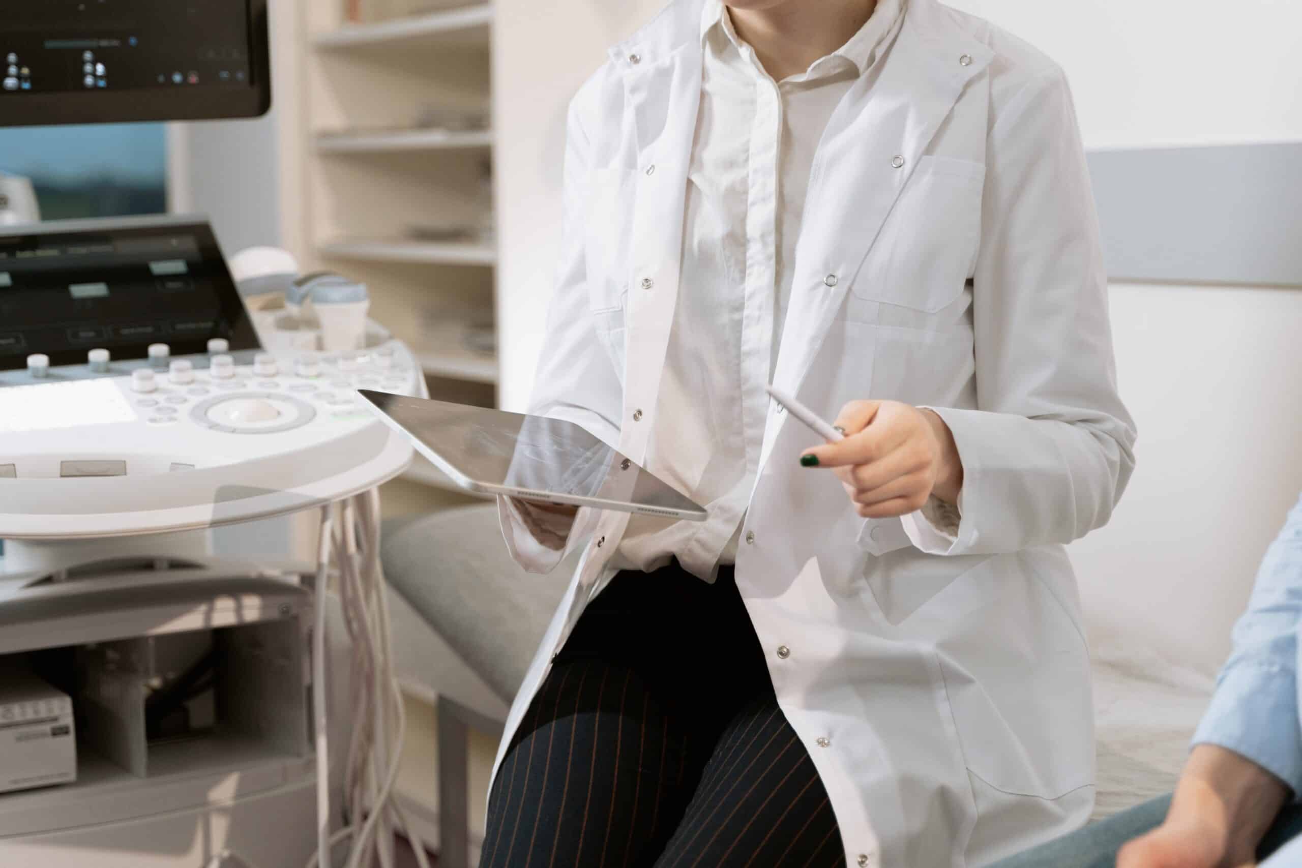 Doctor holding clipboard next to ultrasound machine.
