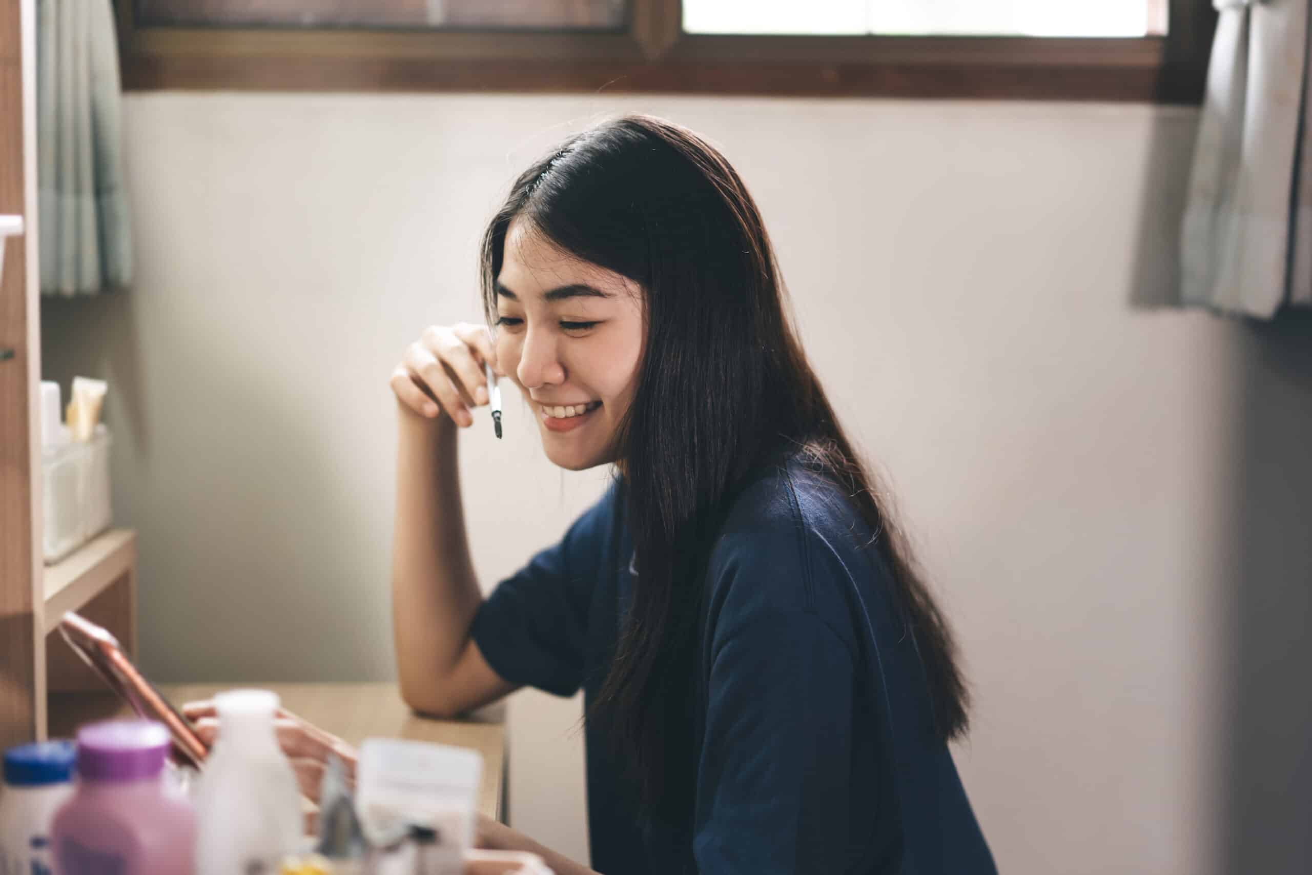 Woman sitting at a desk with painting supplies around her.