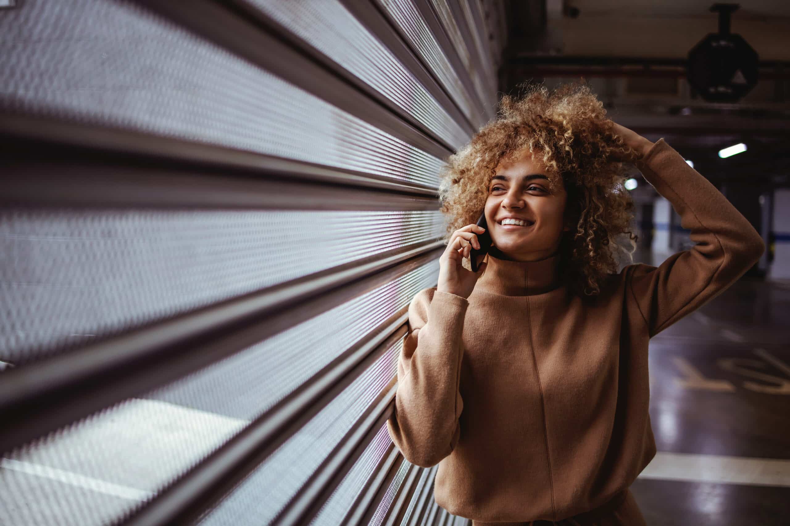 A woman standing near a window with the blinds closed