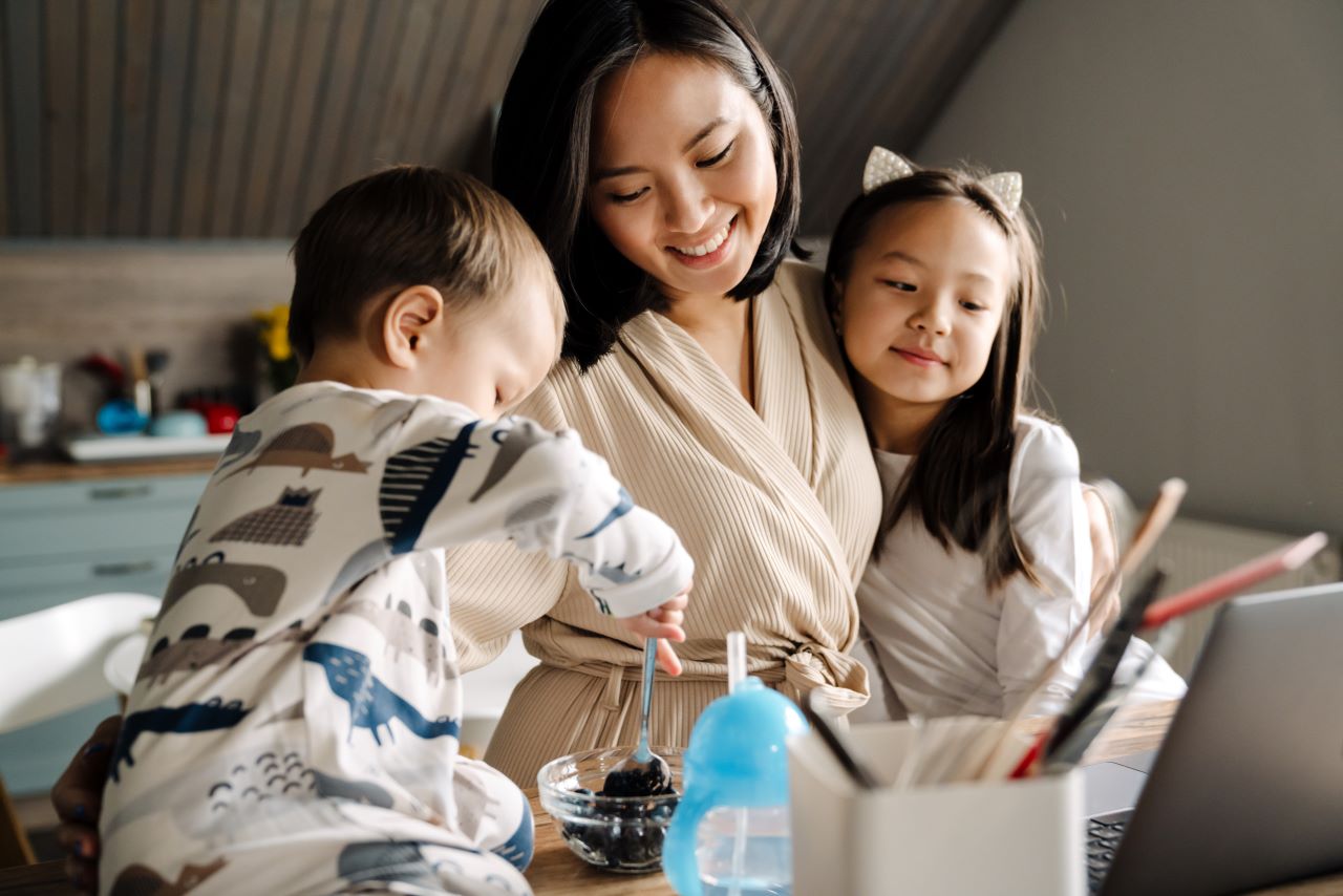 Woman hugging and smiling down at two children