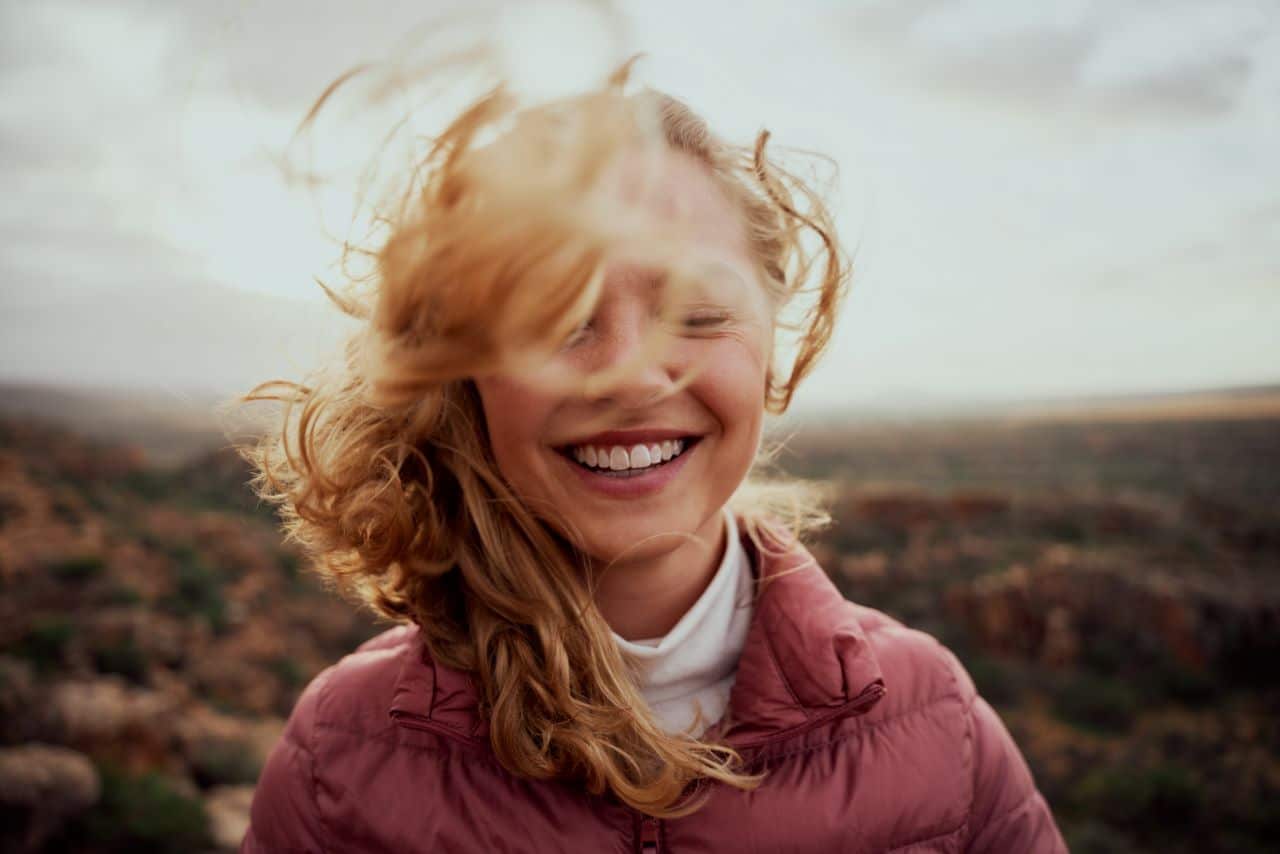Woman smiling with hair blowing in the wind.