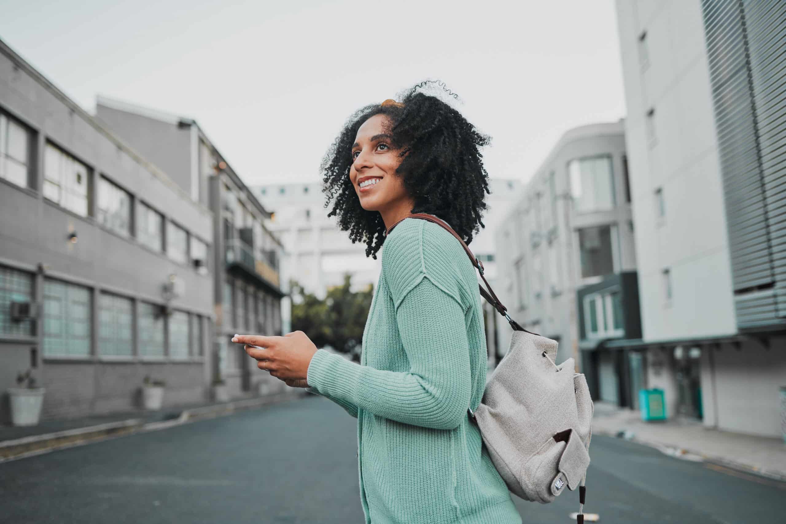 A young woman walking through a city street and looking into the distance