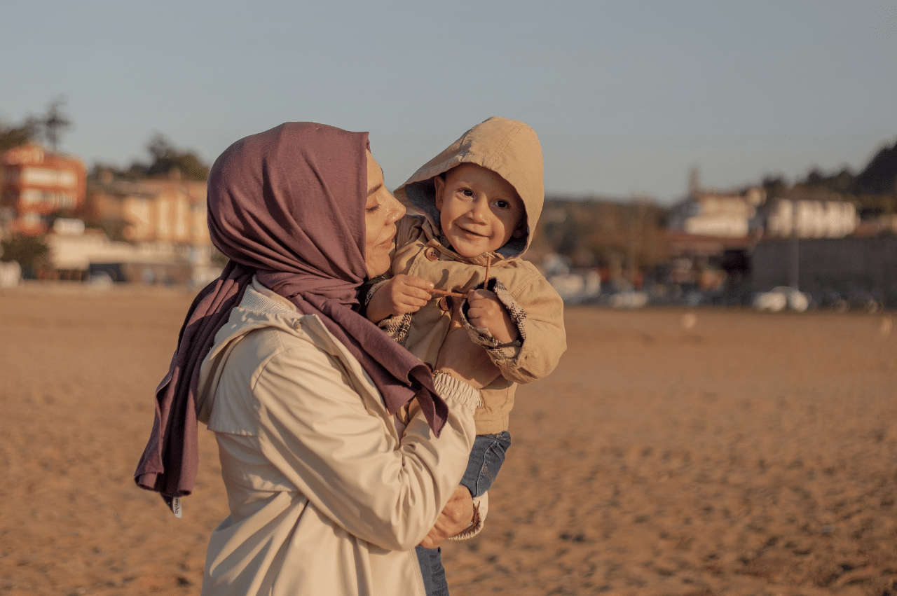 a muslim mother holding her child on the beach