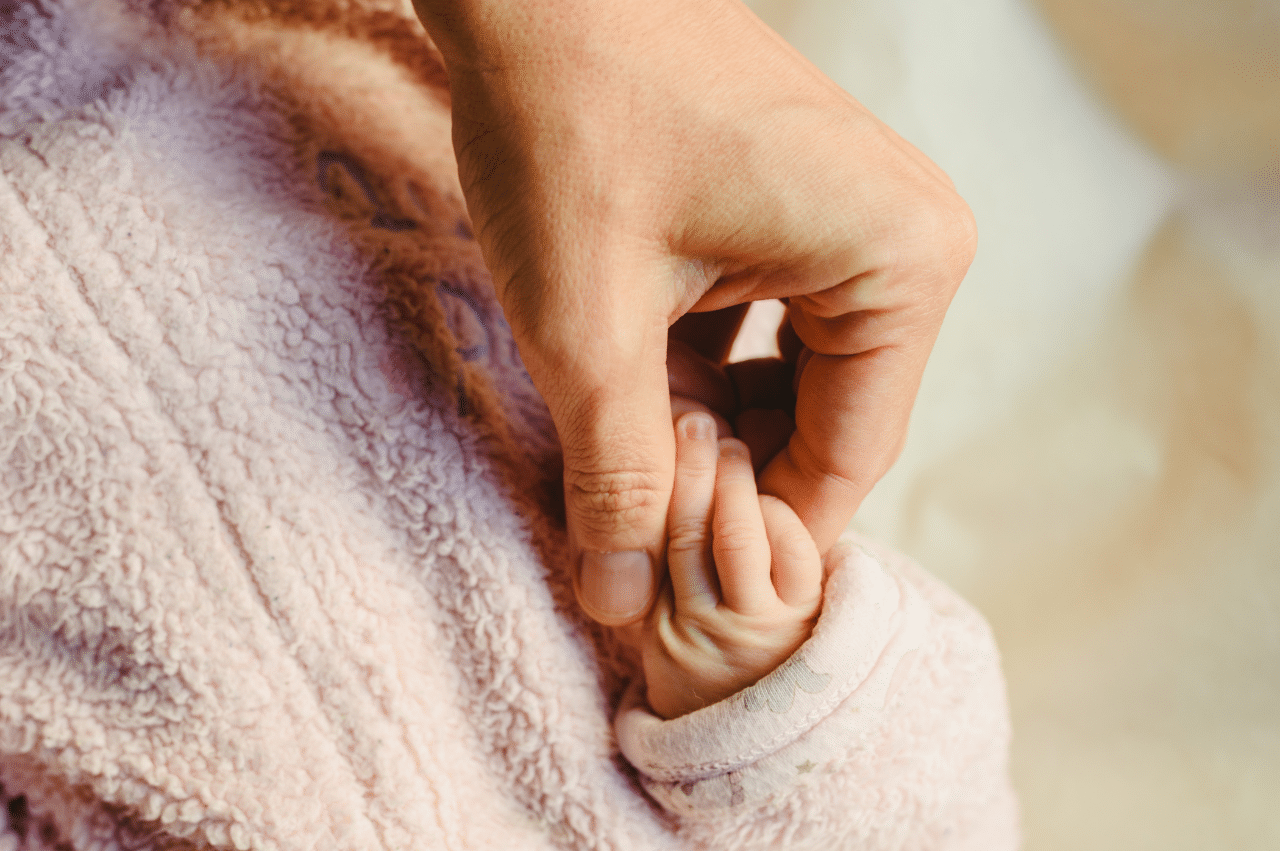 A mother holding her baby's hand
