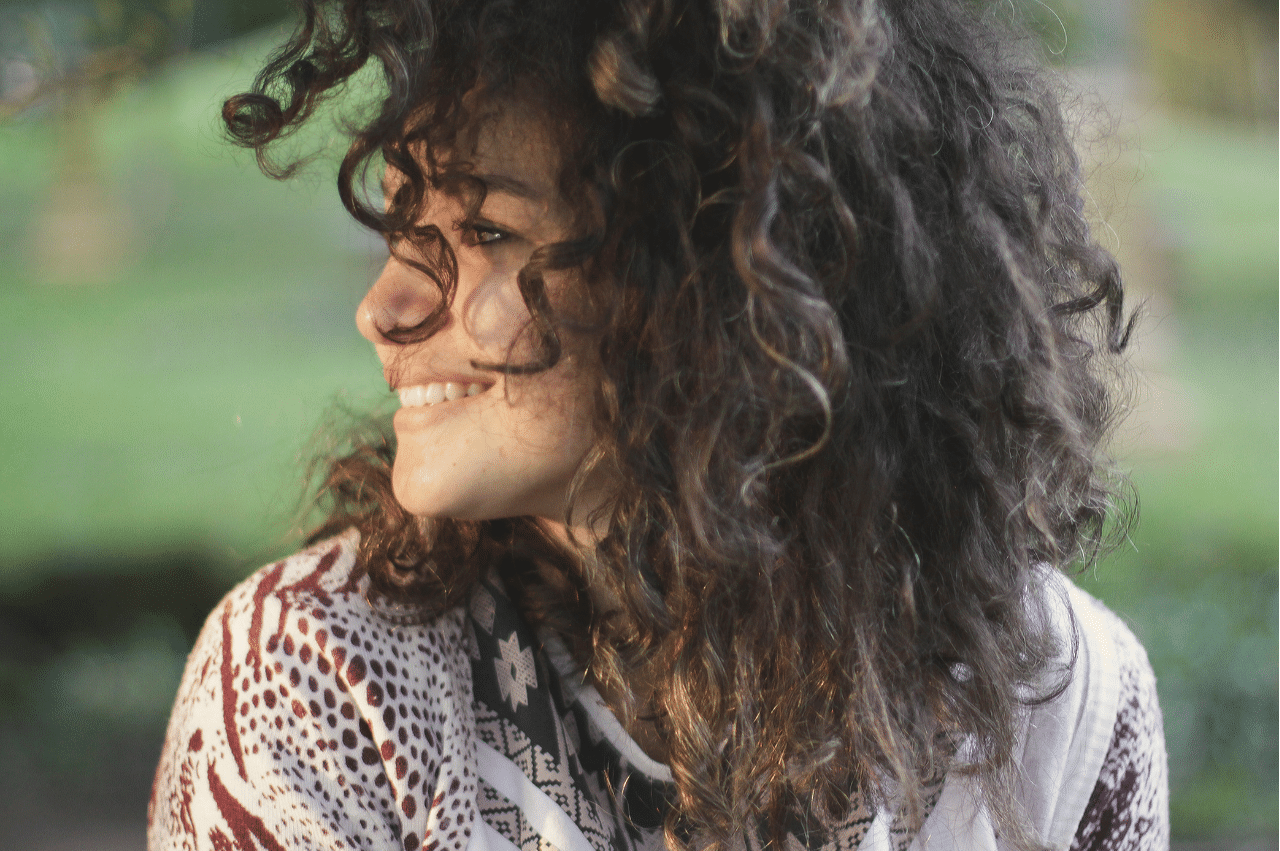 a woman with brown curly hair looking to the left and smiling