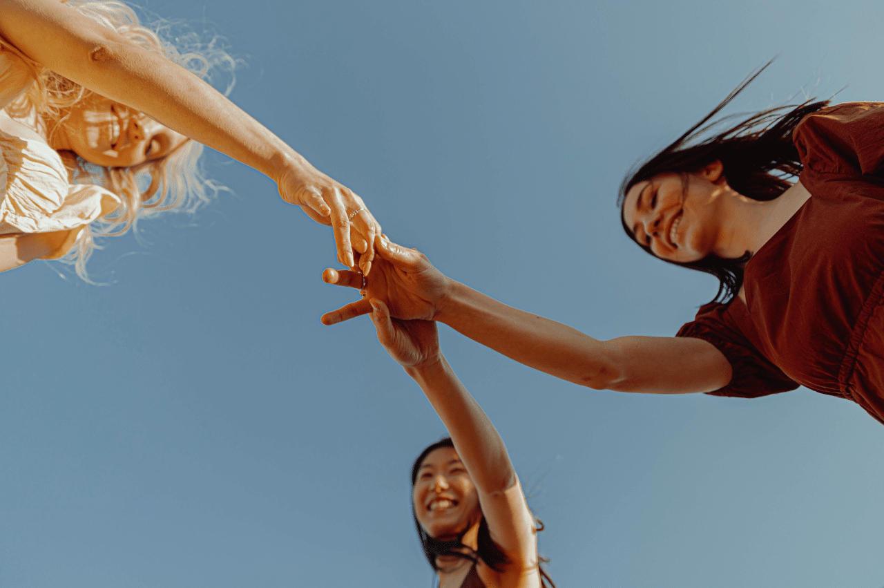 3 women photographed from a worm's eye view holding hands
