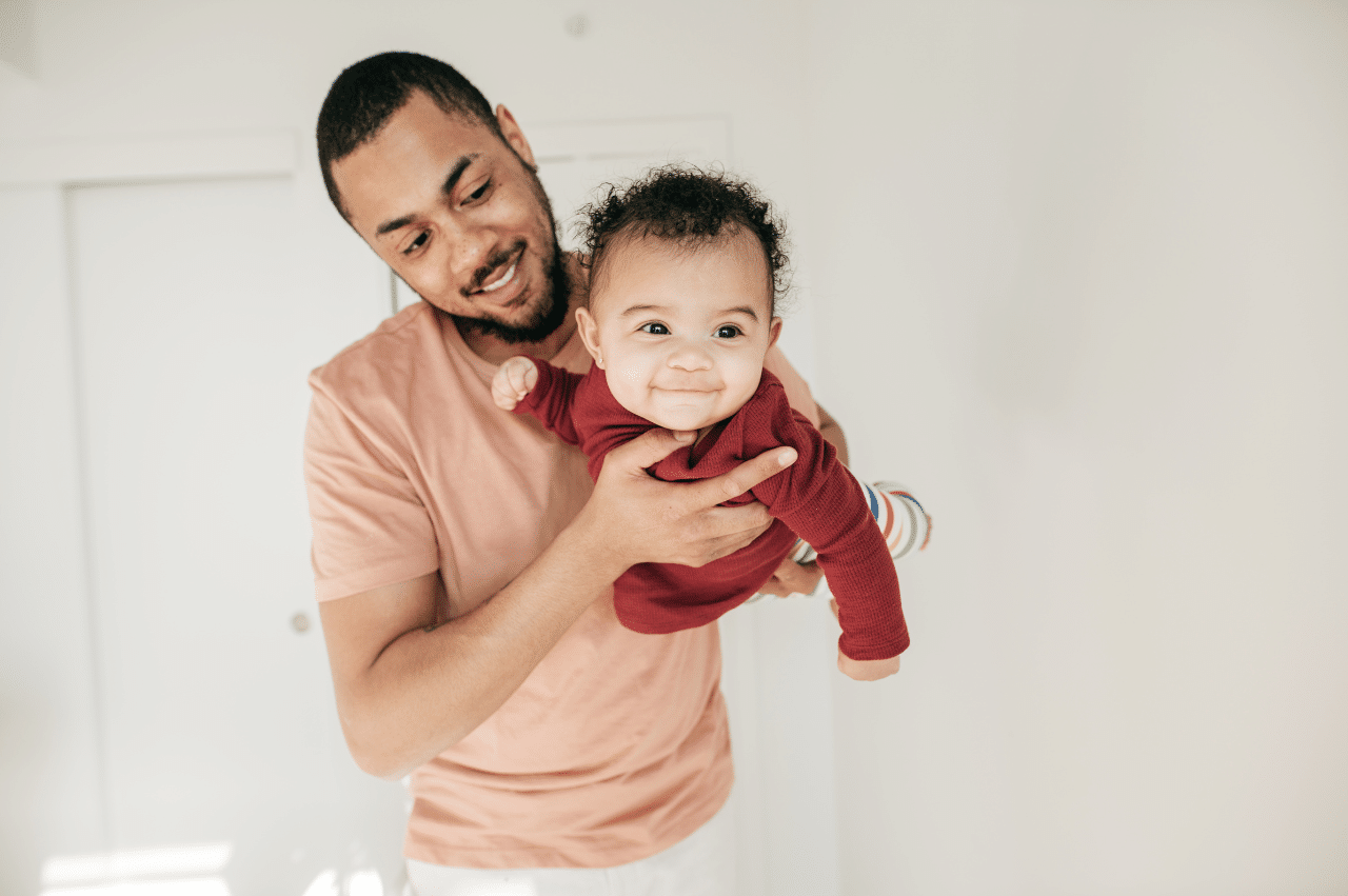 a father holds his child on his stomach to face the camera