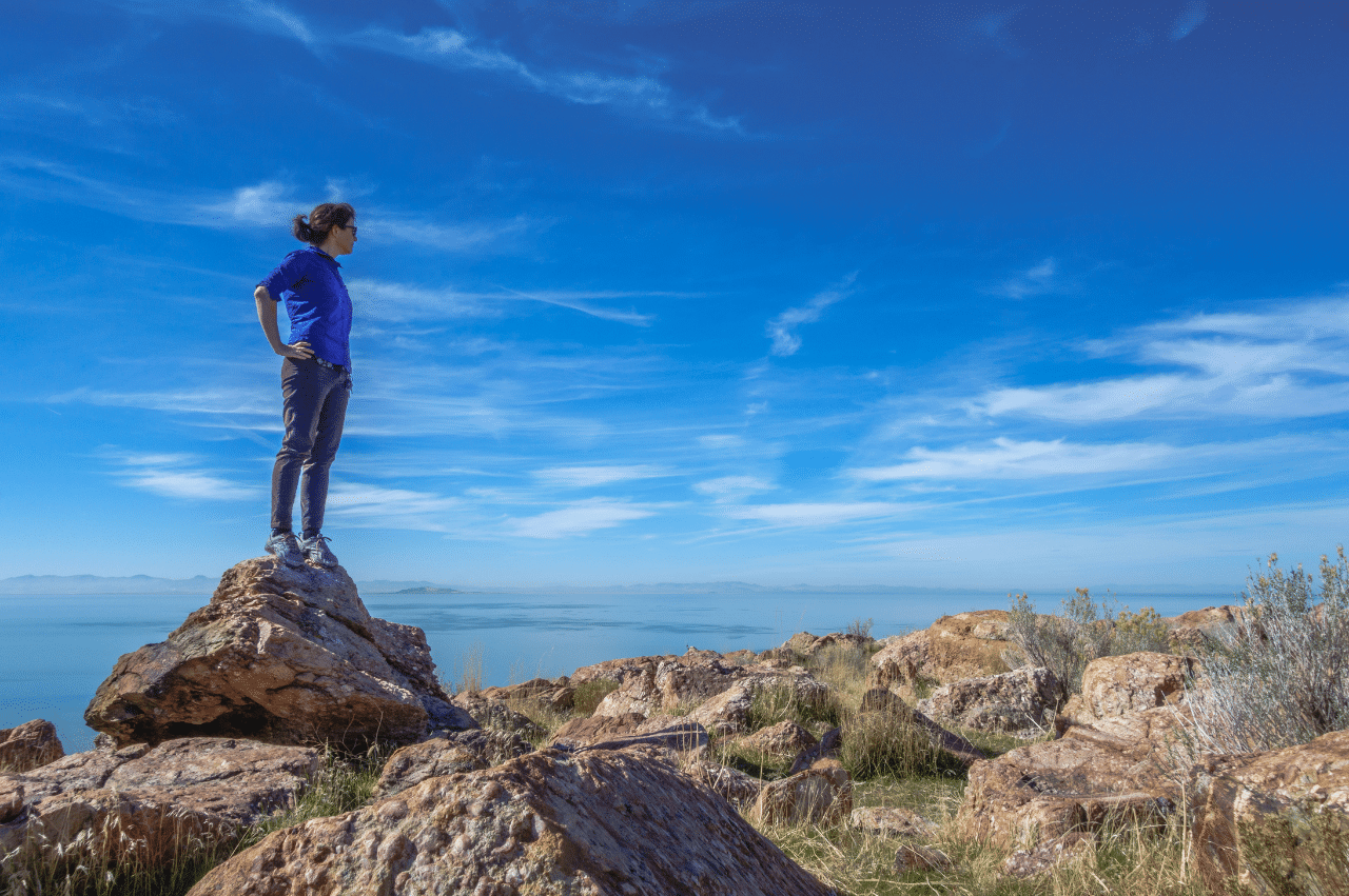 a woman standing at a mountain peak looking out into the distance