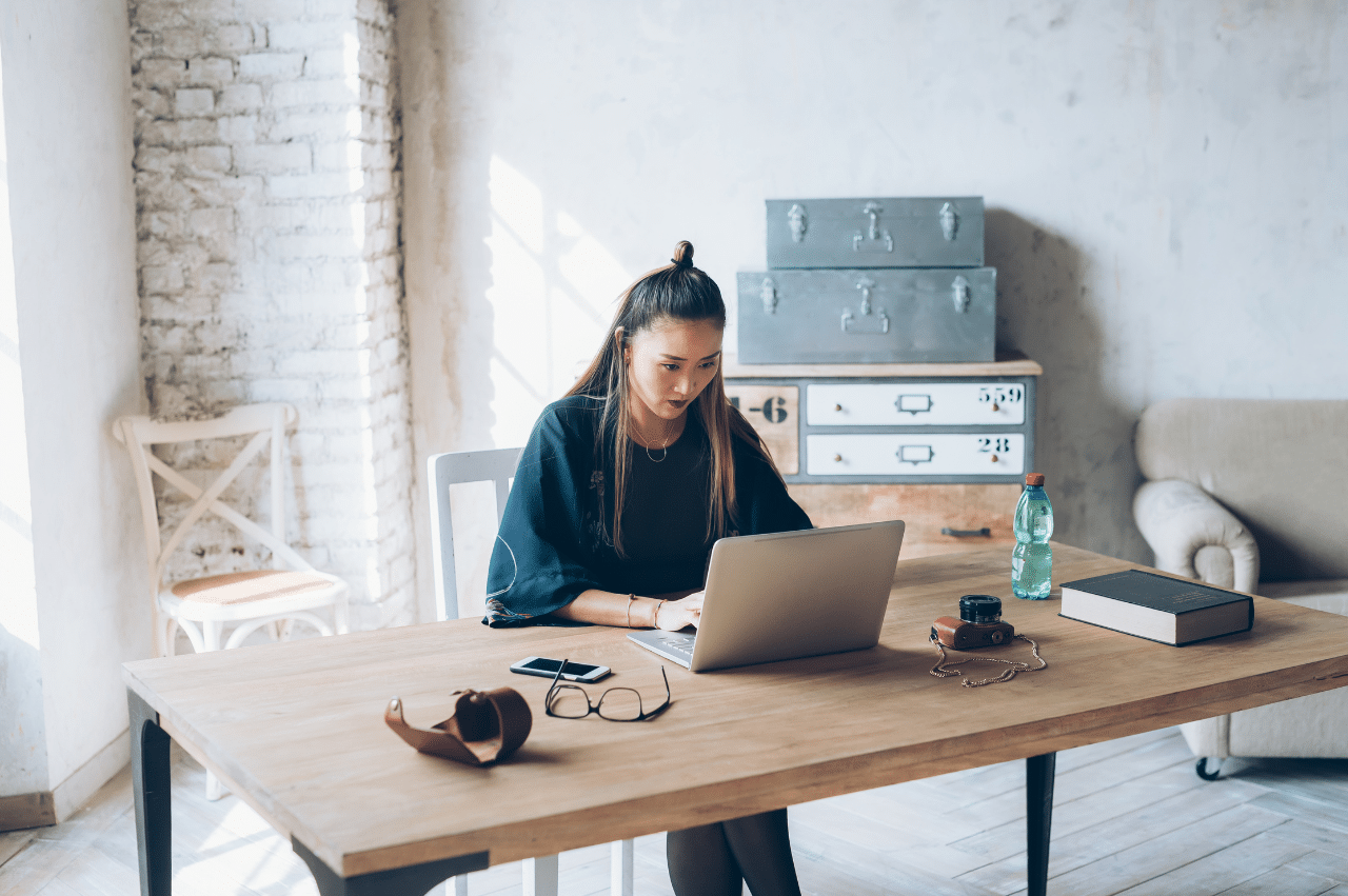 a young woman sitting at a desk in front of her laptop working