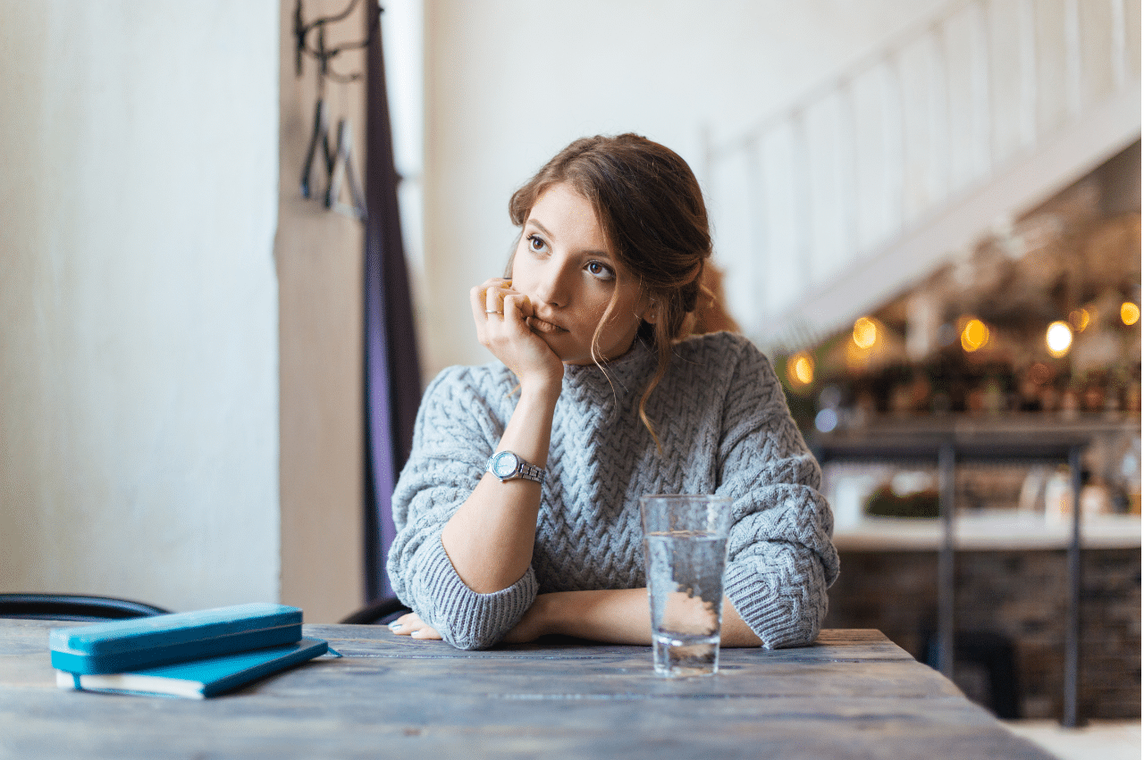 a woman sitting at a desk with her elbow on the table and resting her head on her hand