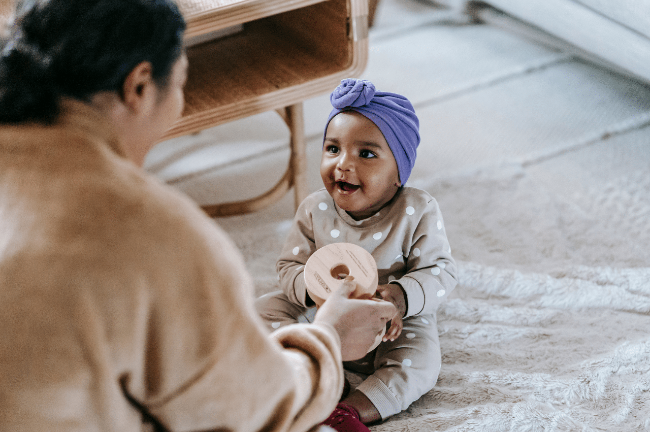 Cute baby playing with mom in forground