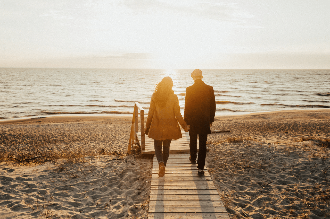 Couple holding hands on a wooden path on a beach
