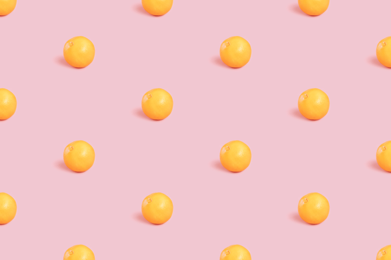 Oranges evenly spaced on a pink background
