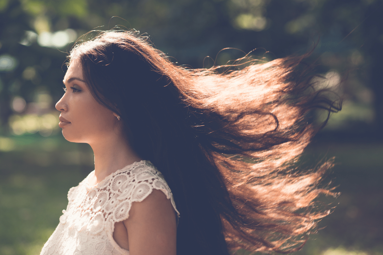 Side profile of a woman with long black hair flowing in the wind