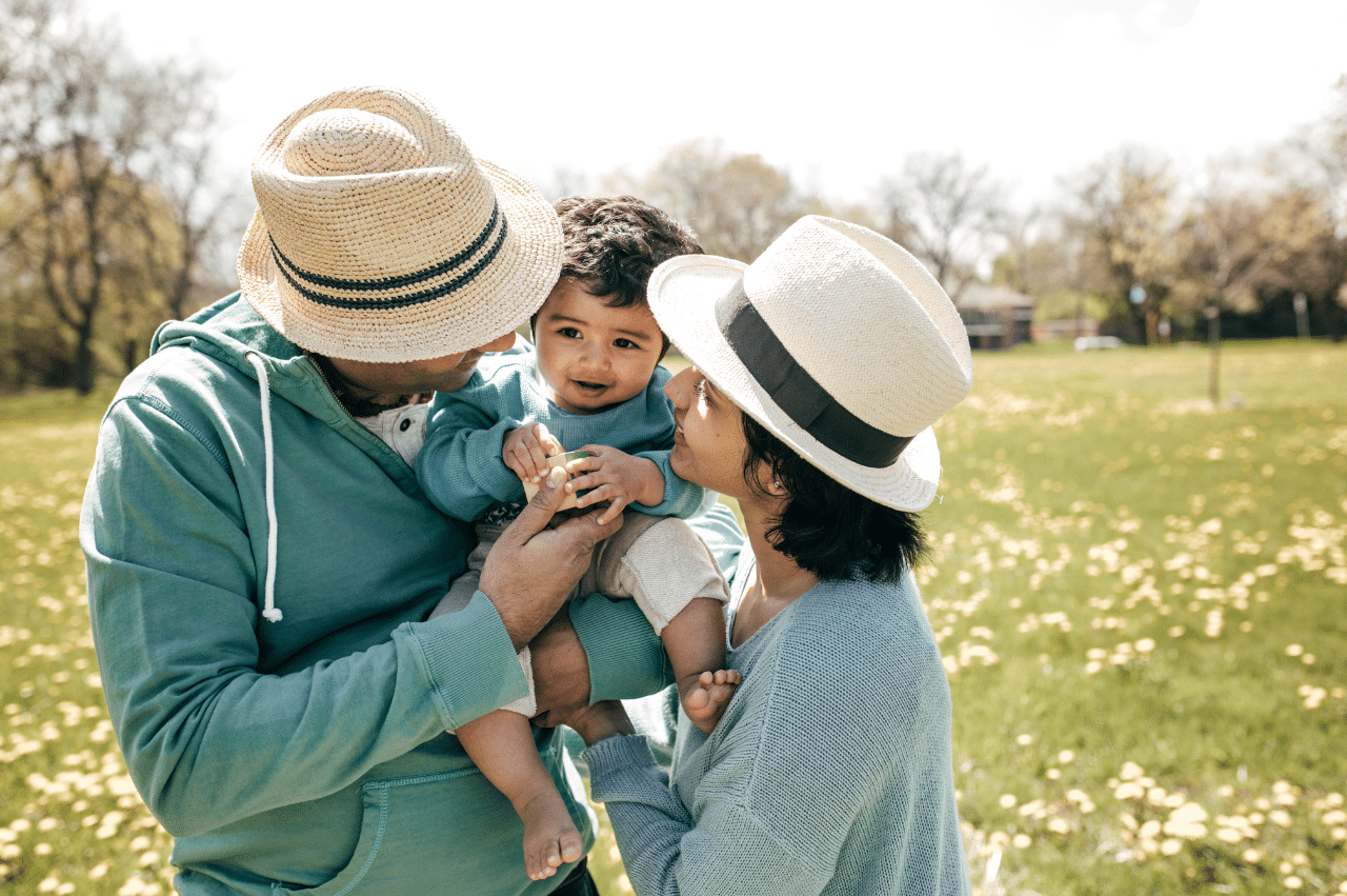 Couple holding a young toddler in a field