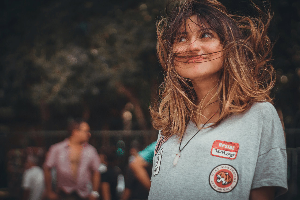Close up of young woman with shoulder length brown hair being blown in the wind and on her face