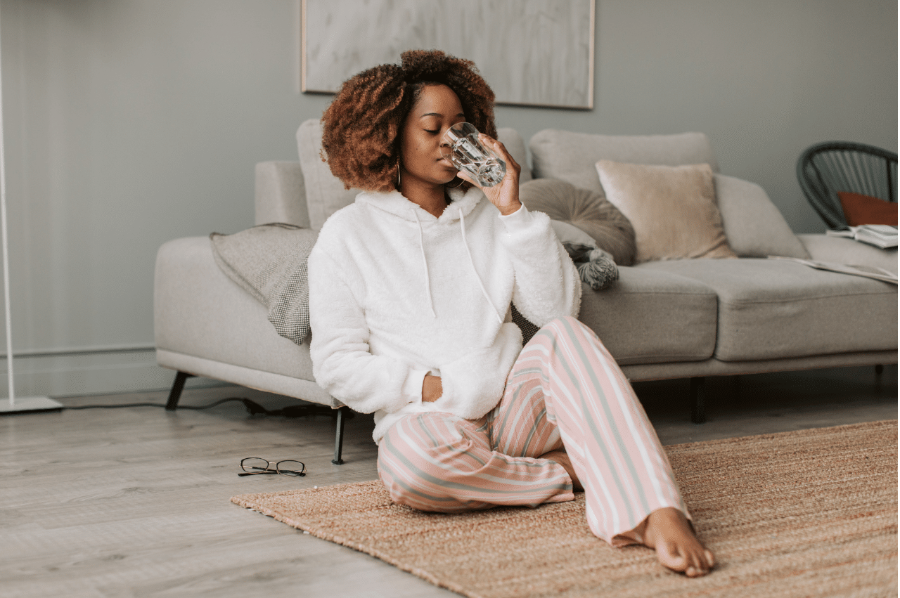 Woman sitting on the floor while leaning on a couch