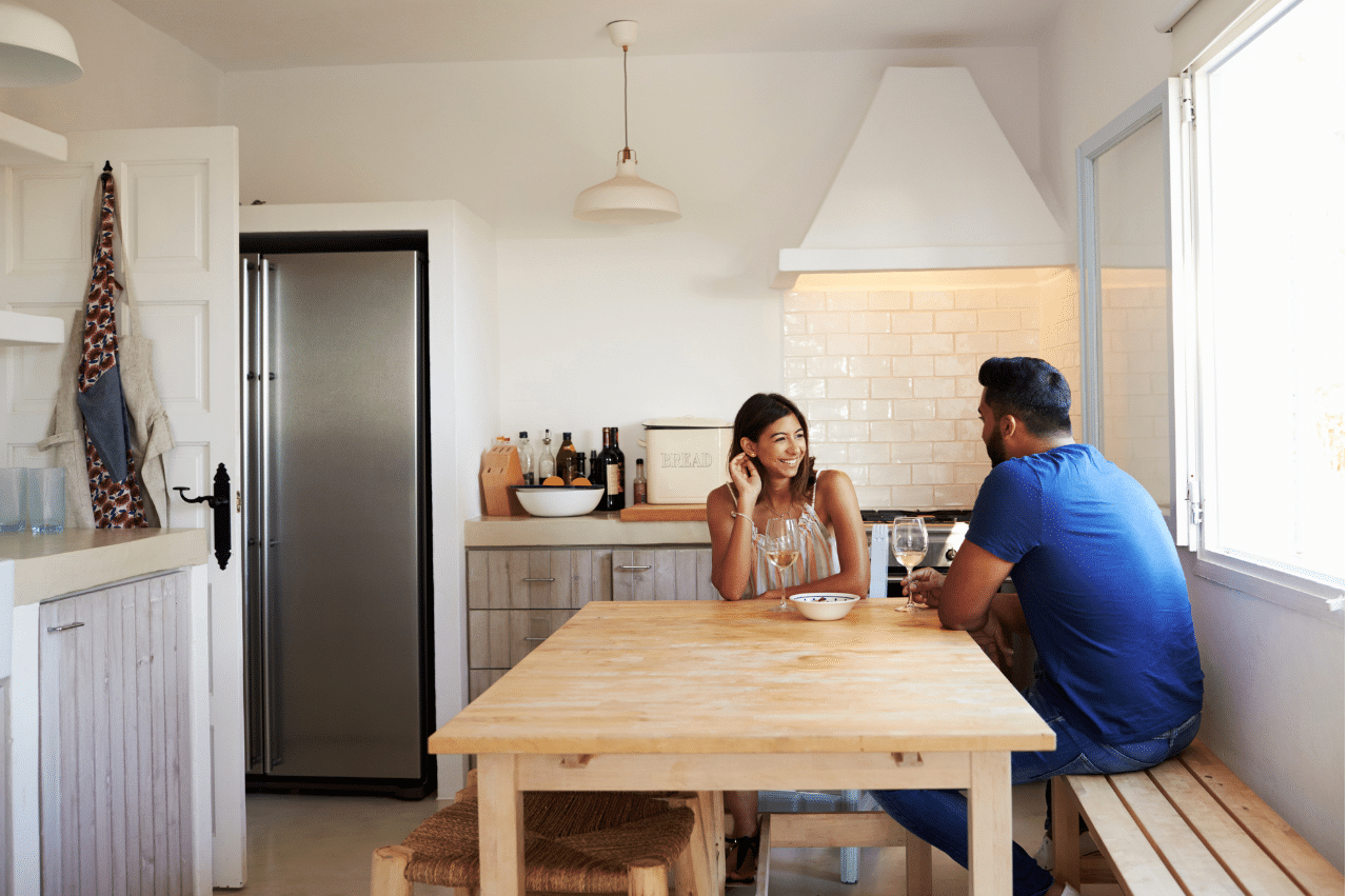 Couple is sitting at a table in a farmhouse style kitchen. Person on the right has their back facing the camera