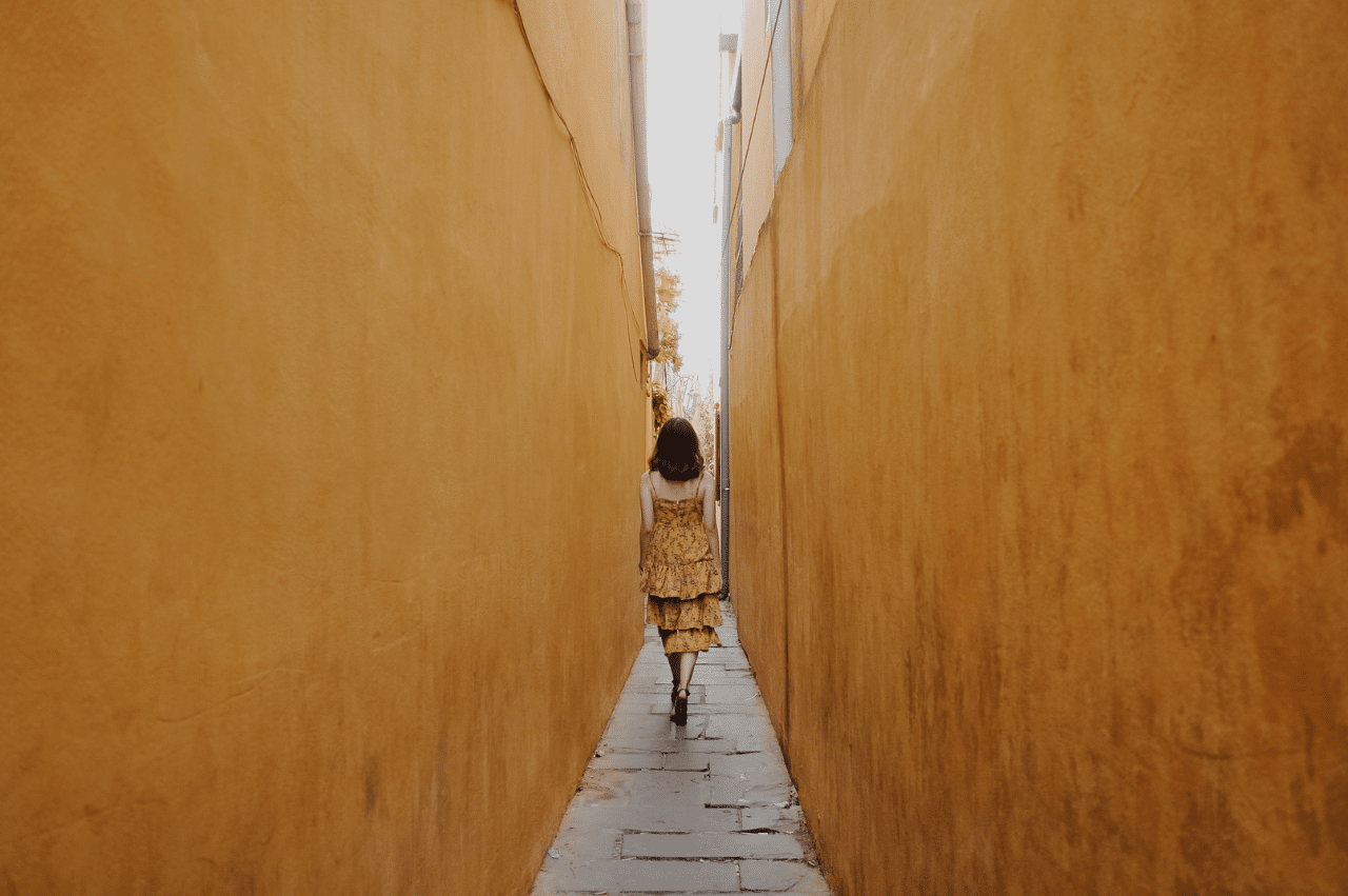 Girl in yellow dress walking down narrow alley
