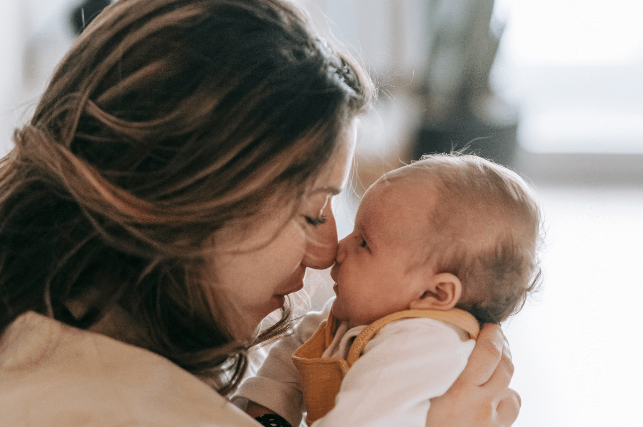 A mom and newborn press noses.