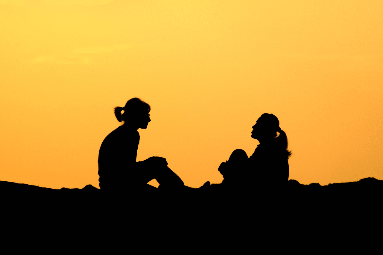 Silhouettes of 2 women sitting