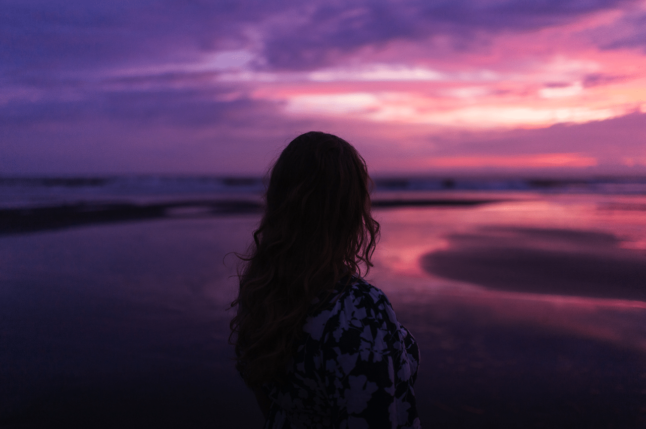 Shadow of a woman looking off into a pink and purple sunset