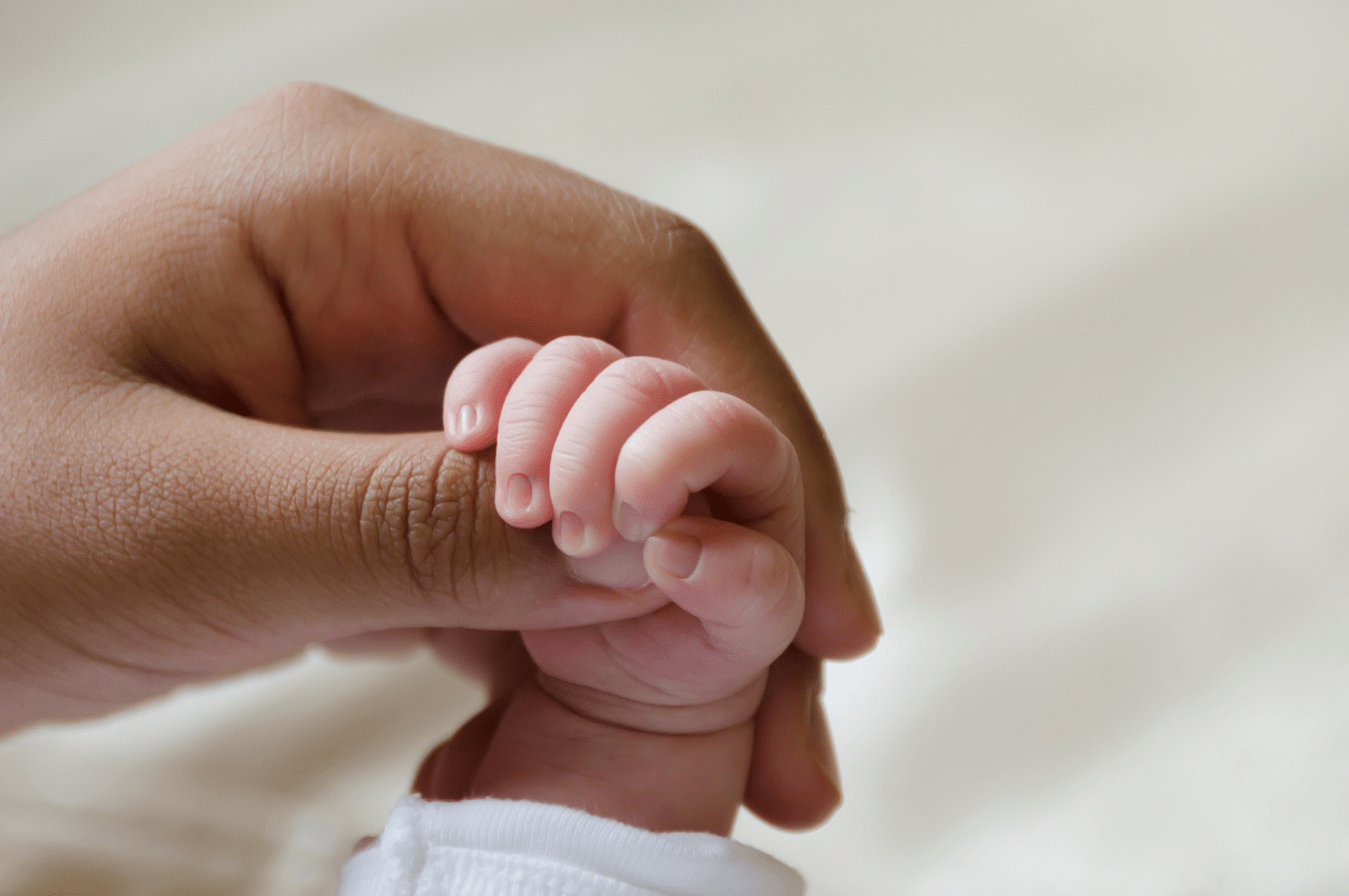 Photo of an adult hand holding a baby hand