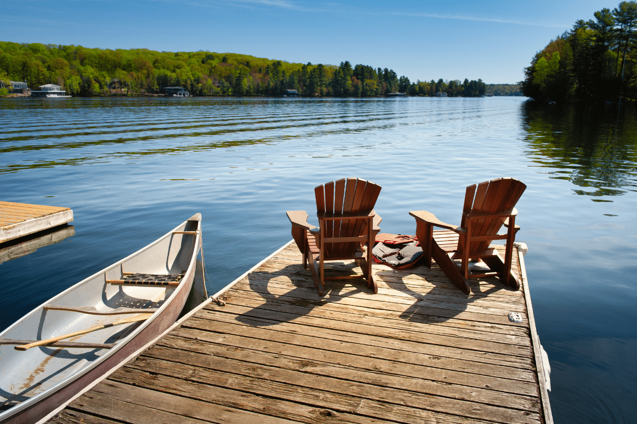 Photo of a dock on a lake with 2 chairs on it.