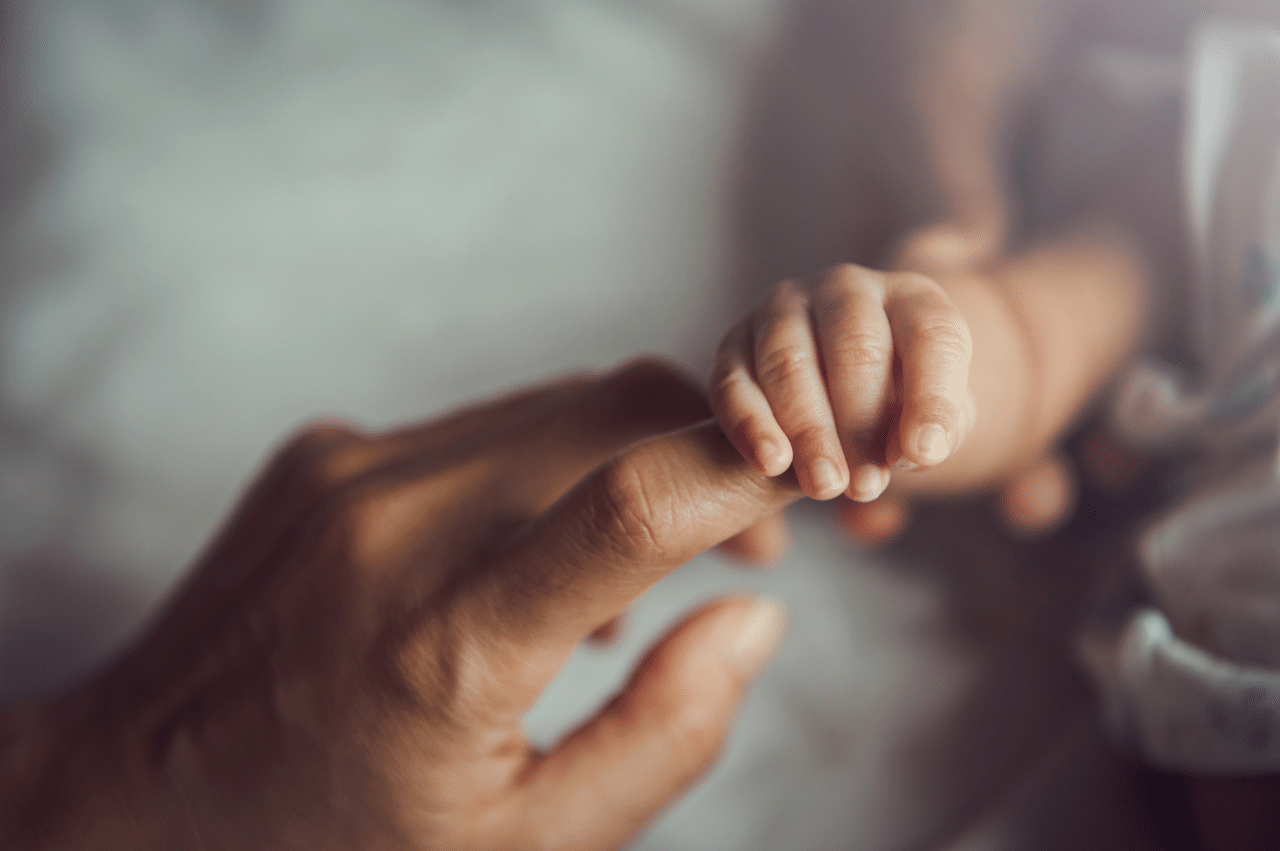 Photo of a newborn holding mother's hand
