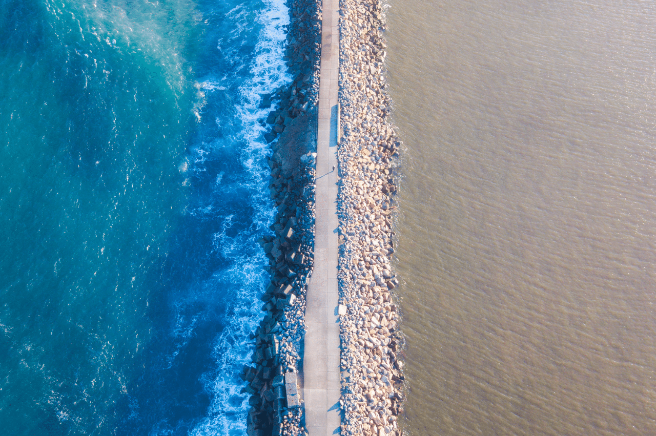Aerial photo of two bodies of water meeting with a bridge in the middle