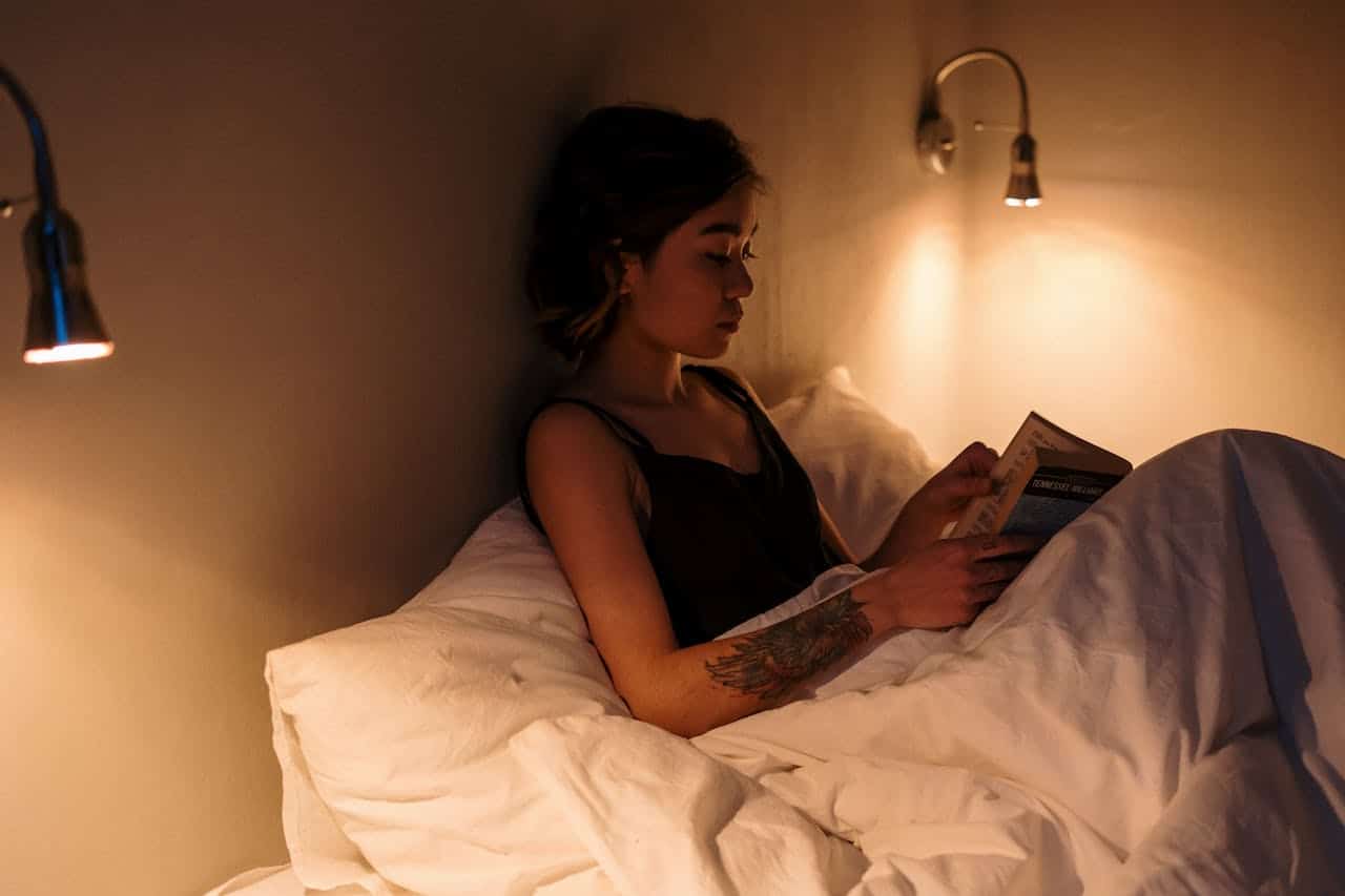 Girl relaxing in bed resting and reading a book