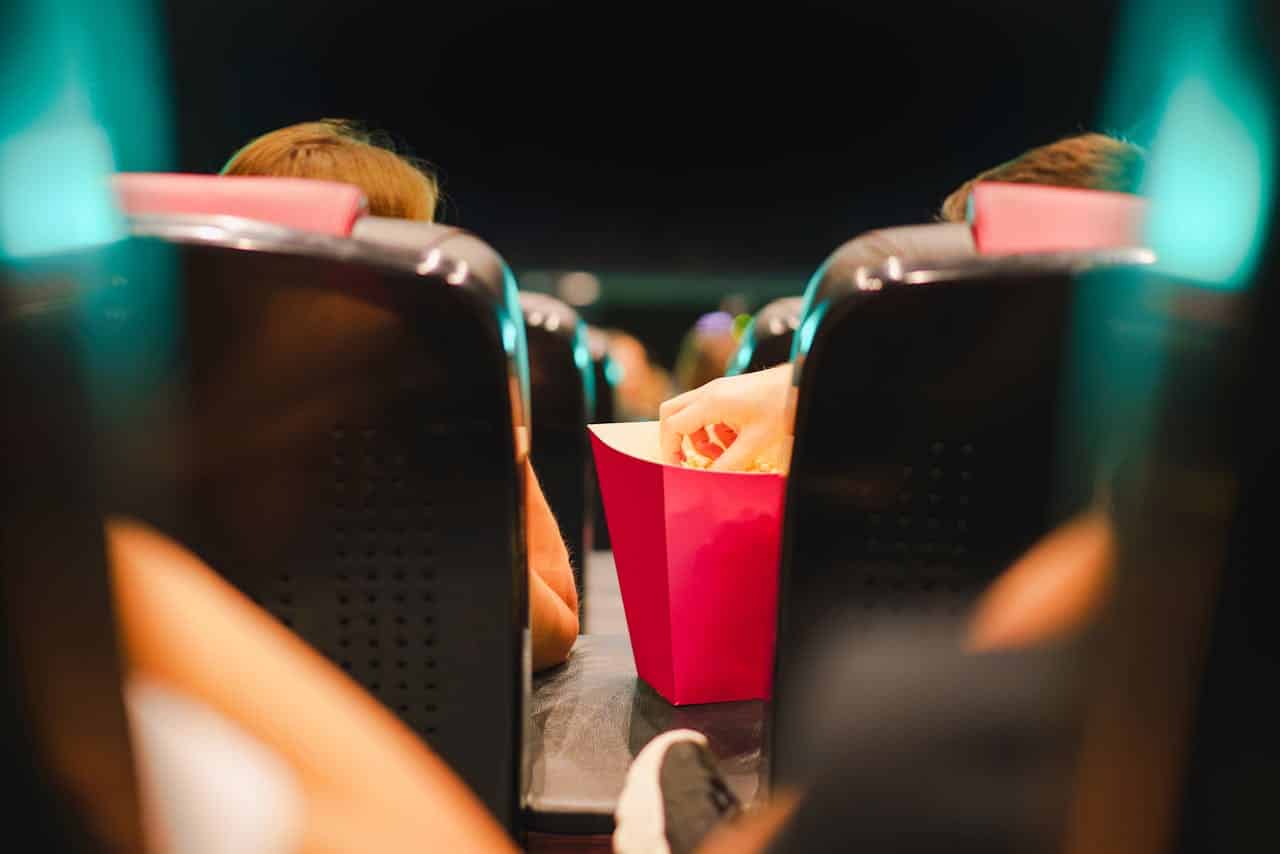 people watching a movie in the movie theater with popcorn
